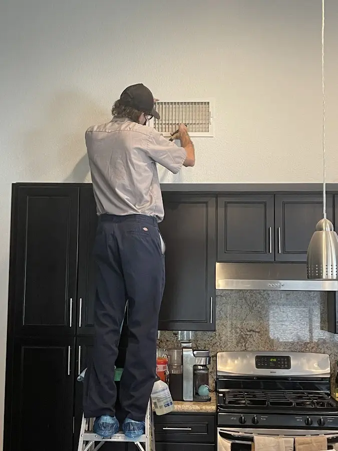 Technician inspecting an air vent during HVAC service in Balch Springs